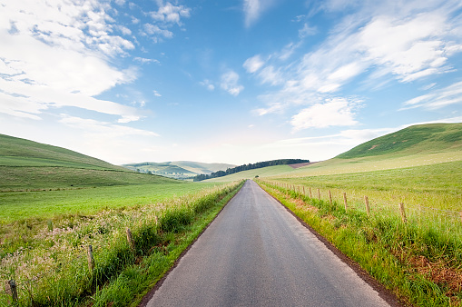 A rural road in the rolling countryside of the Scottish Borders.